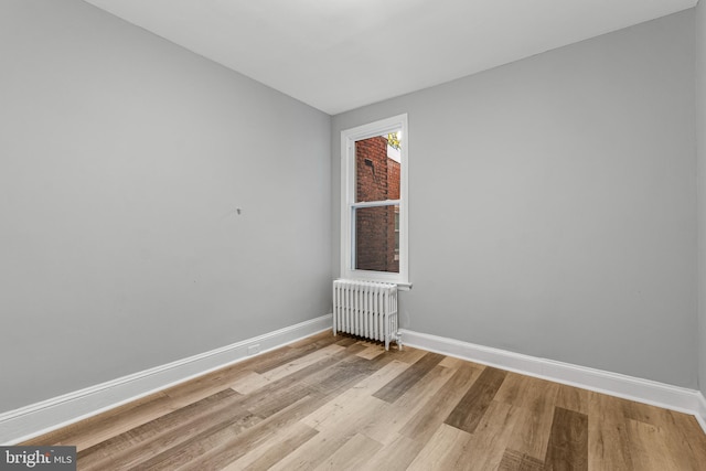 unfurnished room with radiator heating unit and light hardwood / wood-style flooring