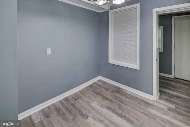 empty room with hardwood / wood-style floors, crown molding, and an inviting chandelier