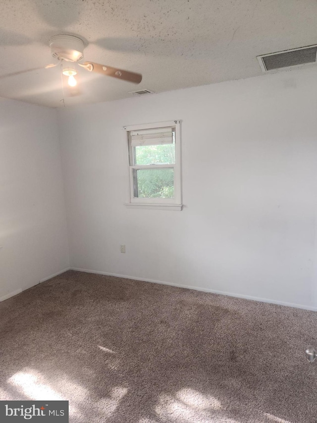 carpeted spare room with visible vents, a textured ceiling, and ceiling fan