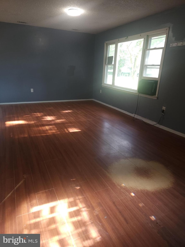 unfurnished room featuring visible vents, a textured ceiling, baseboards, and wood finished floors