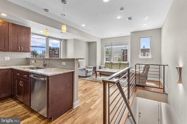 kitchen with pendant lighting, sink, stainless steel dishwasher, tasteful backsplash, and light stone counters