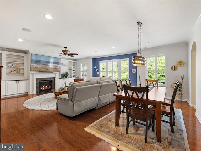 dining room featuring dark hardwood / wood-style floors, built in features, ceiling fan, and ornamental molding