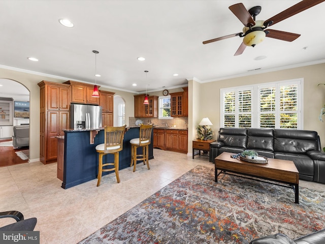 tiled living room featuring ceiling fan and crown molding