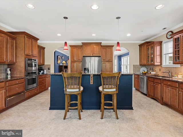 kitchen featuring decorative light fixtures, stainless steel appliances, a breakfast bar area, and dark stone counters