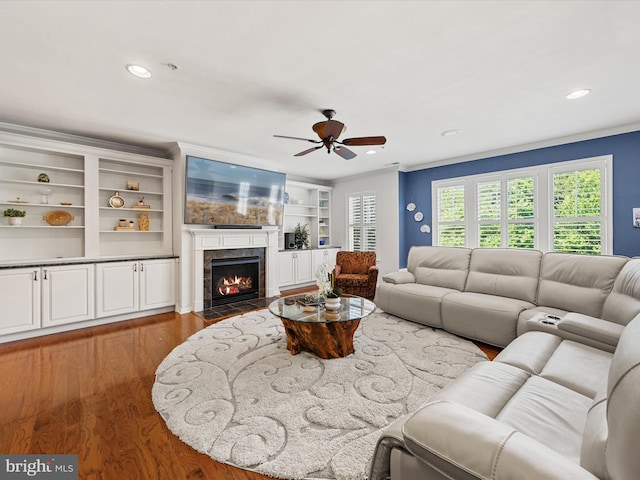 living room with hardwood / wood-style floors, ceiling fan, built in features, and crown molding