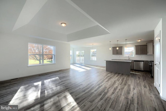 unfurnished living room with dark wood-type flooring, sink, and a tray ceiling