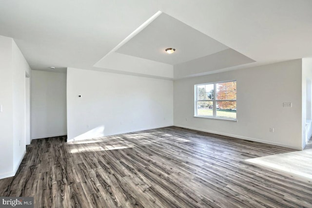 empty room featuring dark wood-type flooring and a tray ceiling