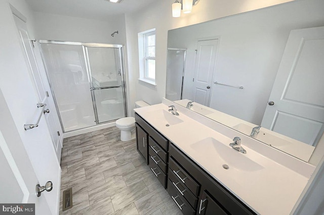 bathroom featuring toilet, an enclosed shower, and vanity