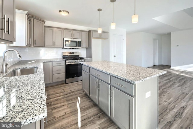 kitchen with appliances with stainless steel finishes, sink, decorative light fixtures, and a center island