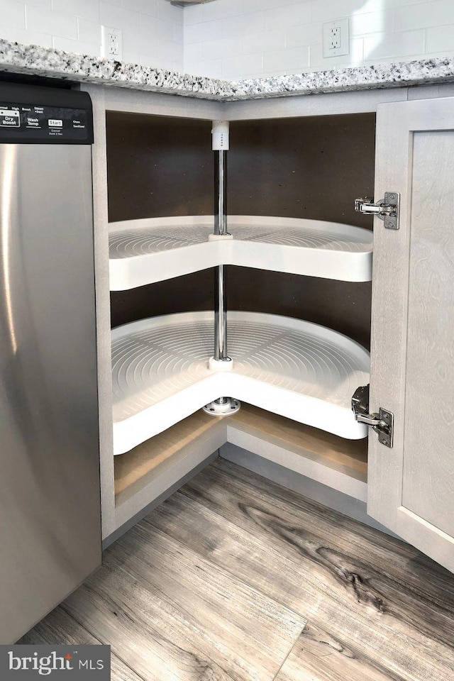 room details featuring light stone countertops, dishwasher, and light hardwood / wood-style floors