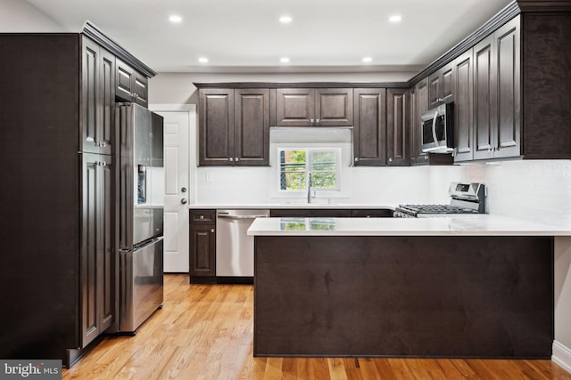 kitchen with sink, light hardwood / wood-style flooring, dark brown cabinetry, kitchen peninsula, and stainless steel appliances