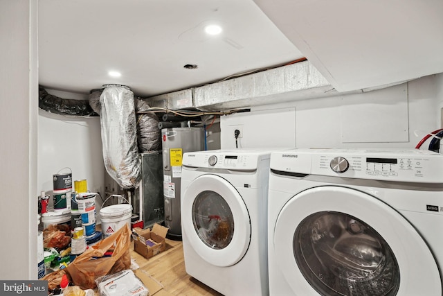 clothes washing area with washing machine and dryer, electric water heater, and light wood-type flooring