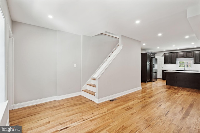 interior space with stainless steel refrigerator with ice dispenser, dark brown cabinetry, and light hardwood / wood-style floors