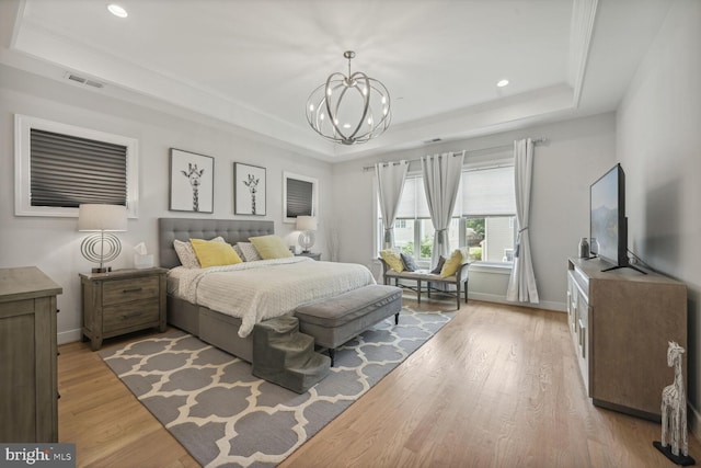 bedroom featuring a chandelier, light hardwood / wood-style floors, and a raised ceiling