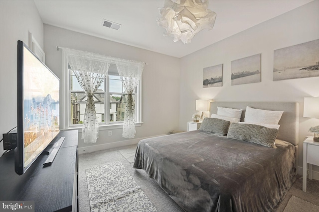 bedroom with light carpet and an inviting chandelier