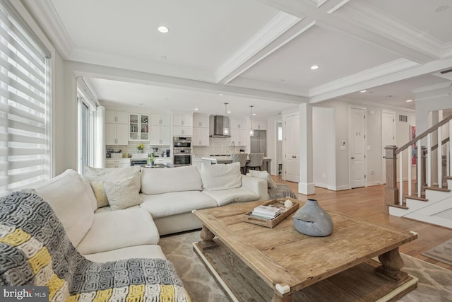 living room with light hardwood / wood-style floors, sink, ornamental molding, and beam ceiling