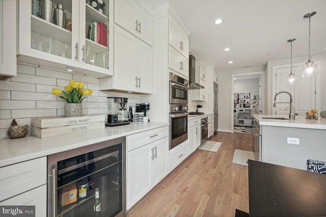 kitchen with backsplash, beverage cooler, sink, pendant lighting, and white cabinetry