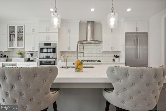 kitchen featuring tasteful backsplash, hanging light fixtures, wall chimney exhaust hood, and stainless steel appliances