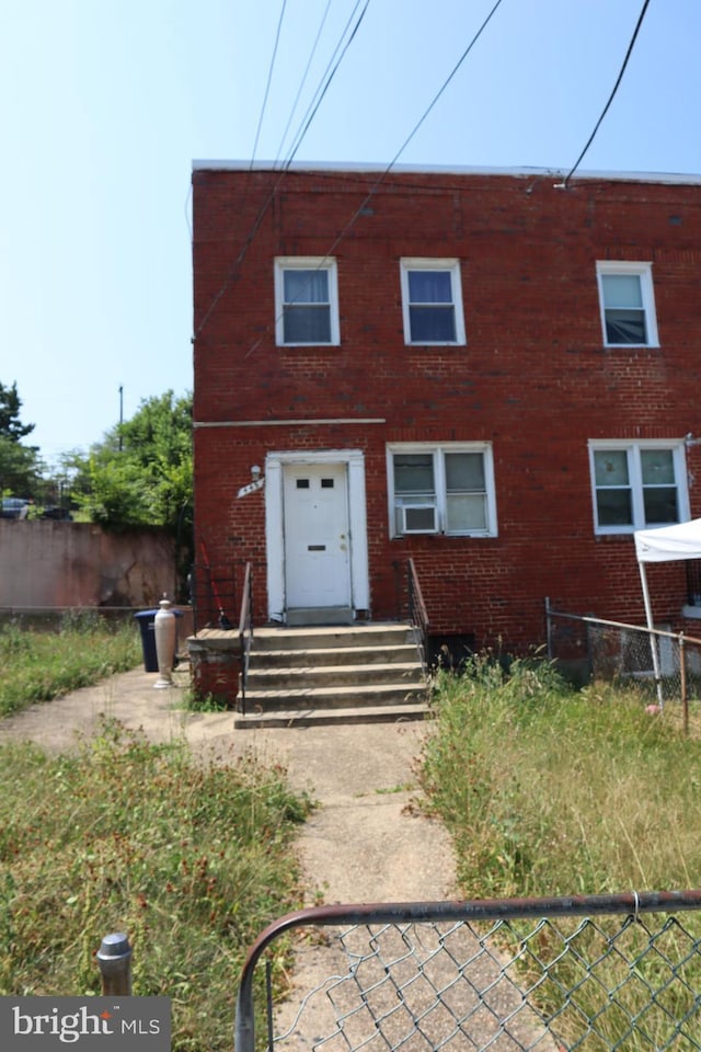 view of front of house with entry steps, brick siding, and fence