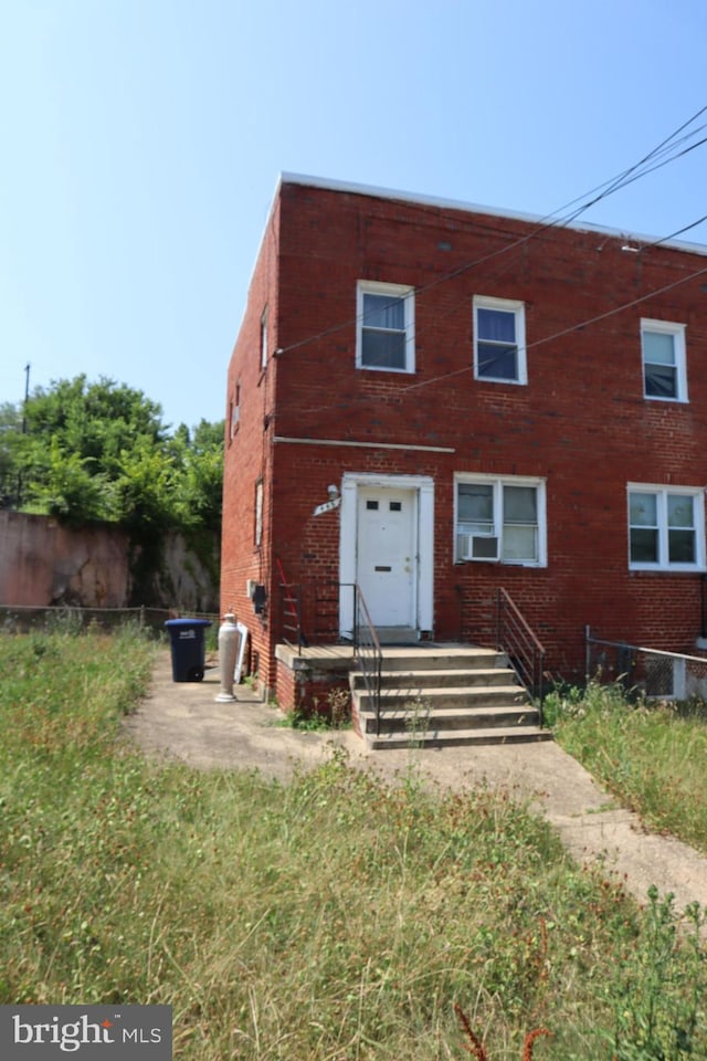 view of front of house with cooling unit, brick siding, and fence