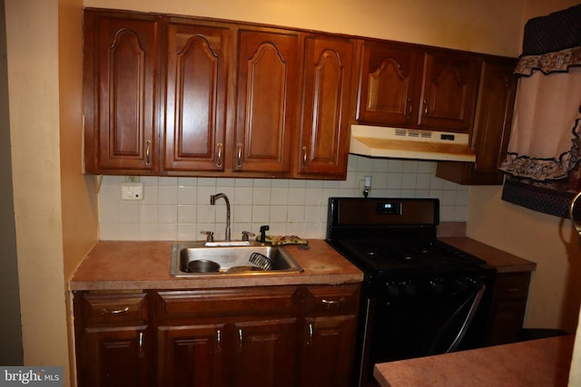 kitchen with light countertops, backsplash, black range with gas stovetop, a sink, and under cabinet range hood