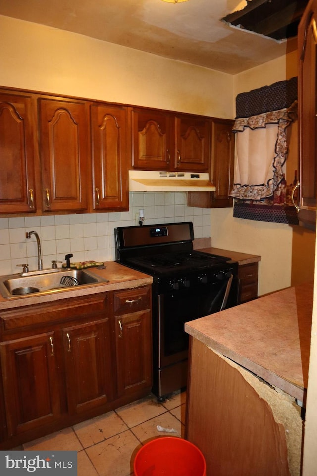 kitchen featuring electric stove, light countertops, decorative backsplash, a sink, and under cabinet range hood