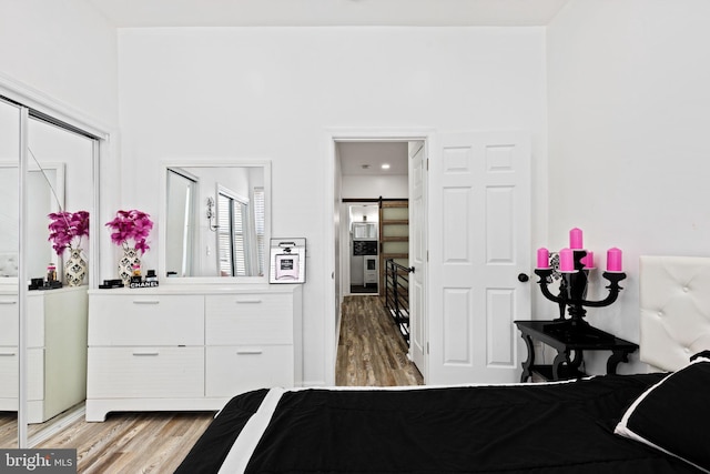 bedroom with a barn door, a closet, and wood-type flooring