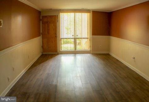 empty room featuring crown molding and dark wood-type flooring