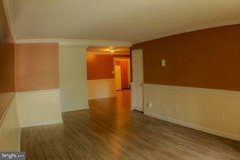 empty room with wood-type flooring and ornamental molding