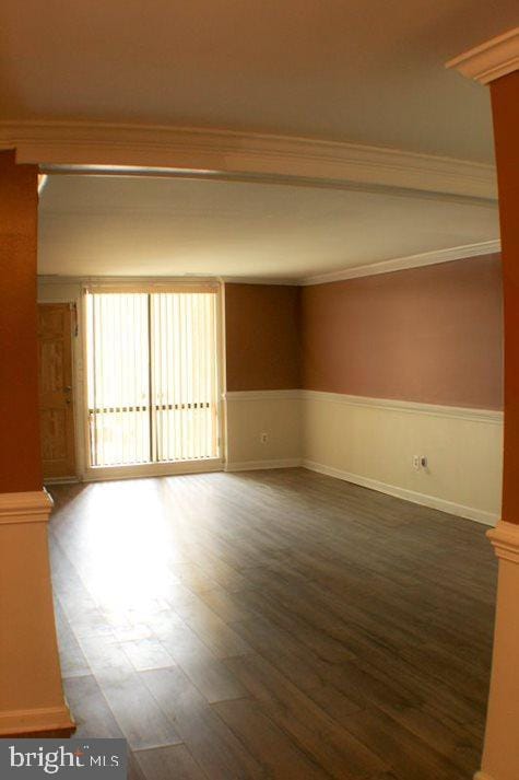 empty room featuring ornamental molding and dark wood-type flooring