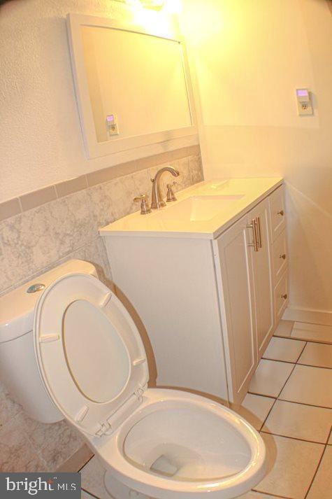 bathroom featuring tile patterned flooring, vanity, tile walls, and toilet