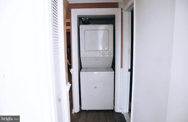 laundry room with dark hardwood / wood-style floors and stacked washing maching and dryer