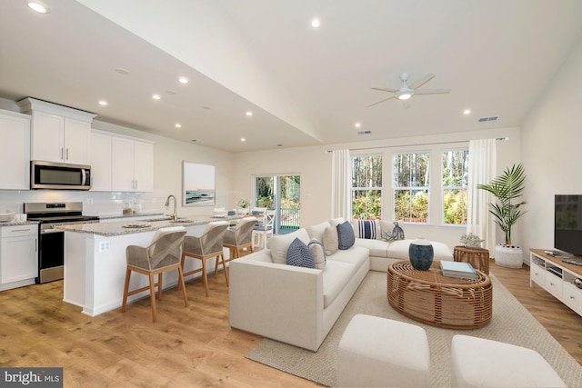 living room featuring ceiling fan, light hardwood / wood-style flooring, lofted ceiling, and sink