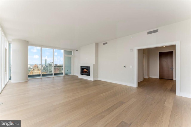 unfurnished living room featuring light wood-type flooring and a wall of windows