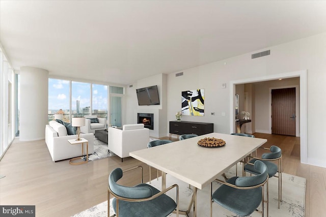 dining area with floor to ceiling windows and light hardwood / wood-style floors