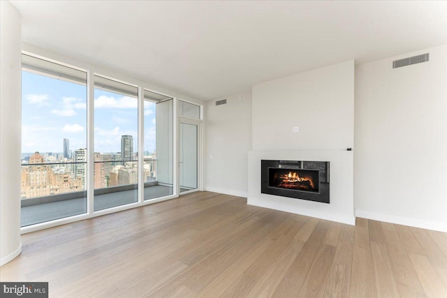 unfurnished living room featuring floor to ceiling windows and hardwood / wood-style flooring