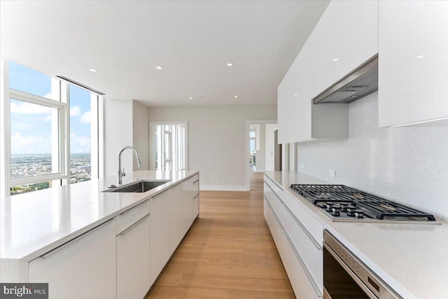 kitchen with sink, white cabinets, light hardwood / wood-style flooring, and stainless steel gas cooktop