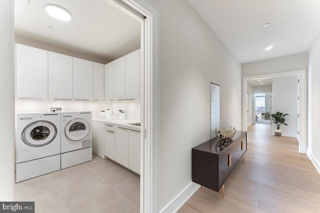 clothes washing area with washer and clothes dryer and cabinets