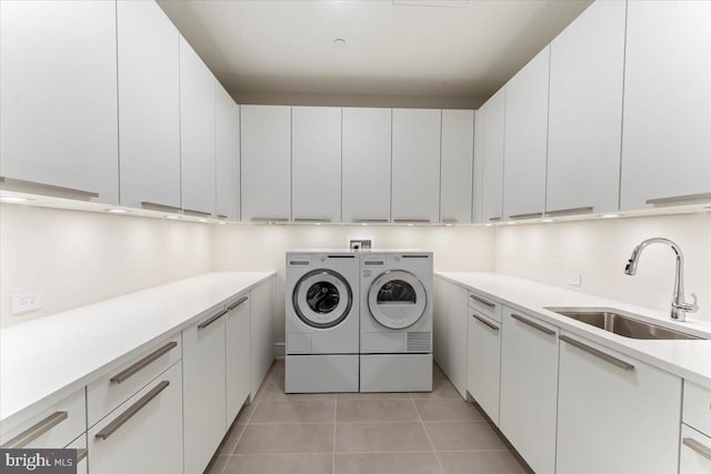 clothes washing area featuring washer and dryer, cabinets, light tile patterned floors, and sink