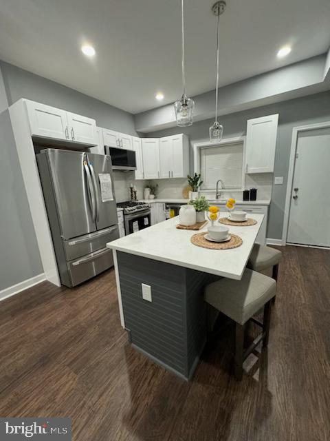 kitchen featuring pendant lighting, white cabinetry, dark wood-type flooring, and appliances with stainless steel finishes