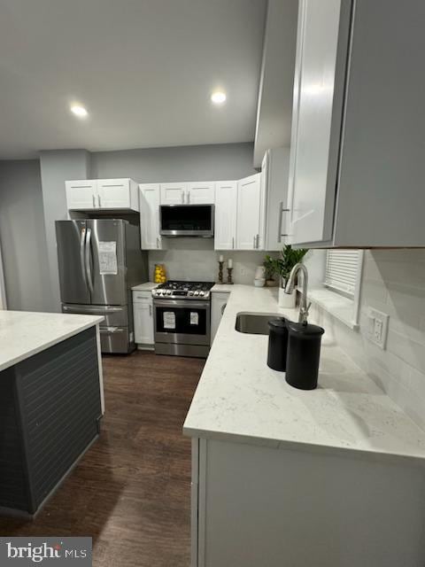 kitchen featuring tasteful backsplash, white cabinetry, sink, and stainless steel appliances