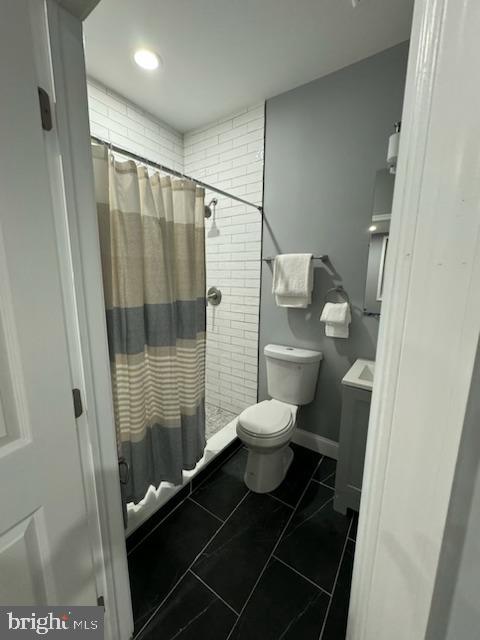 bathroom featuring tile patterned flooring, a shower with curtain, toilet, and vanity