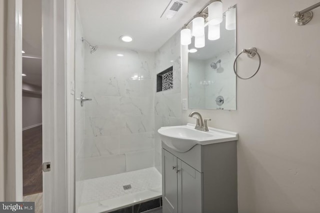 bathroom with a tile shower and vanity