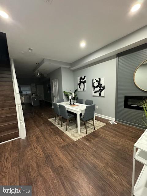 dining space featuring dark hardwood / wood-style flooring and a large fireplace