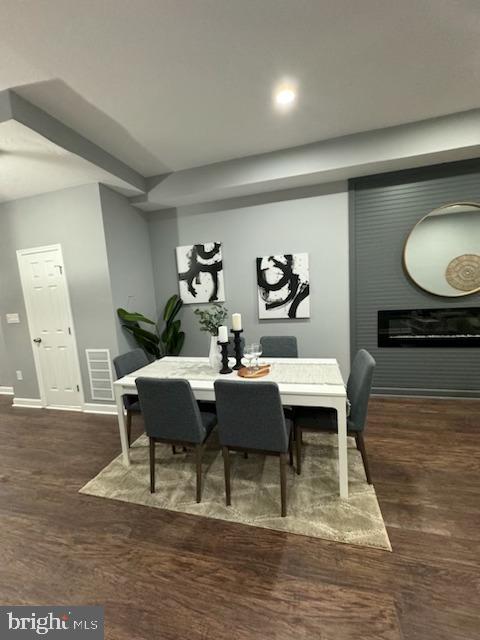 dining area with a large fireplace and dark hardwood / wood-style floors