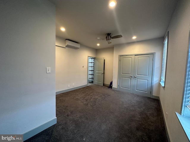 unfurnished bedroom featuring dark carpet, a closet, a wall unit AC, and ceiling fan