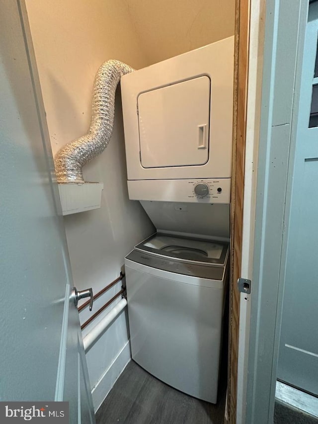 clothes washing area with stacked washer / dryer and dark hardwood / wood-style flooring