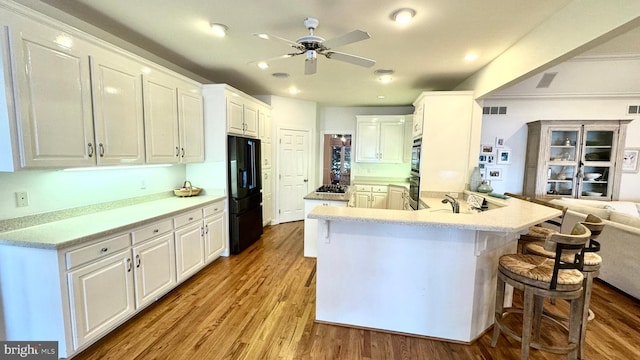 kitchen featuring light hardwood / wood-style flooring, white cabinets, and black appliances