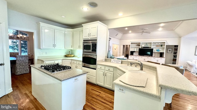 kitchen with white cabinets, a kitchen island, appliances with stainless steel finishes, vaulted ceiling, and sink