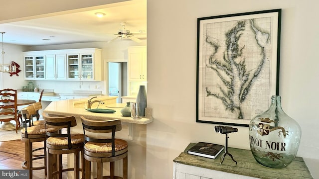 kitchen with ceiling fan, hardwood / wood-style flooring, a breakfast bar area, and white cabinets